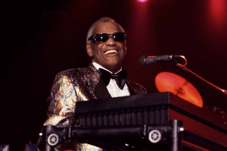Ray Charles smiles as he plays the piano.