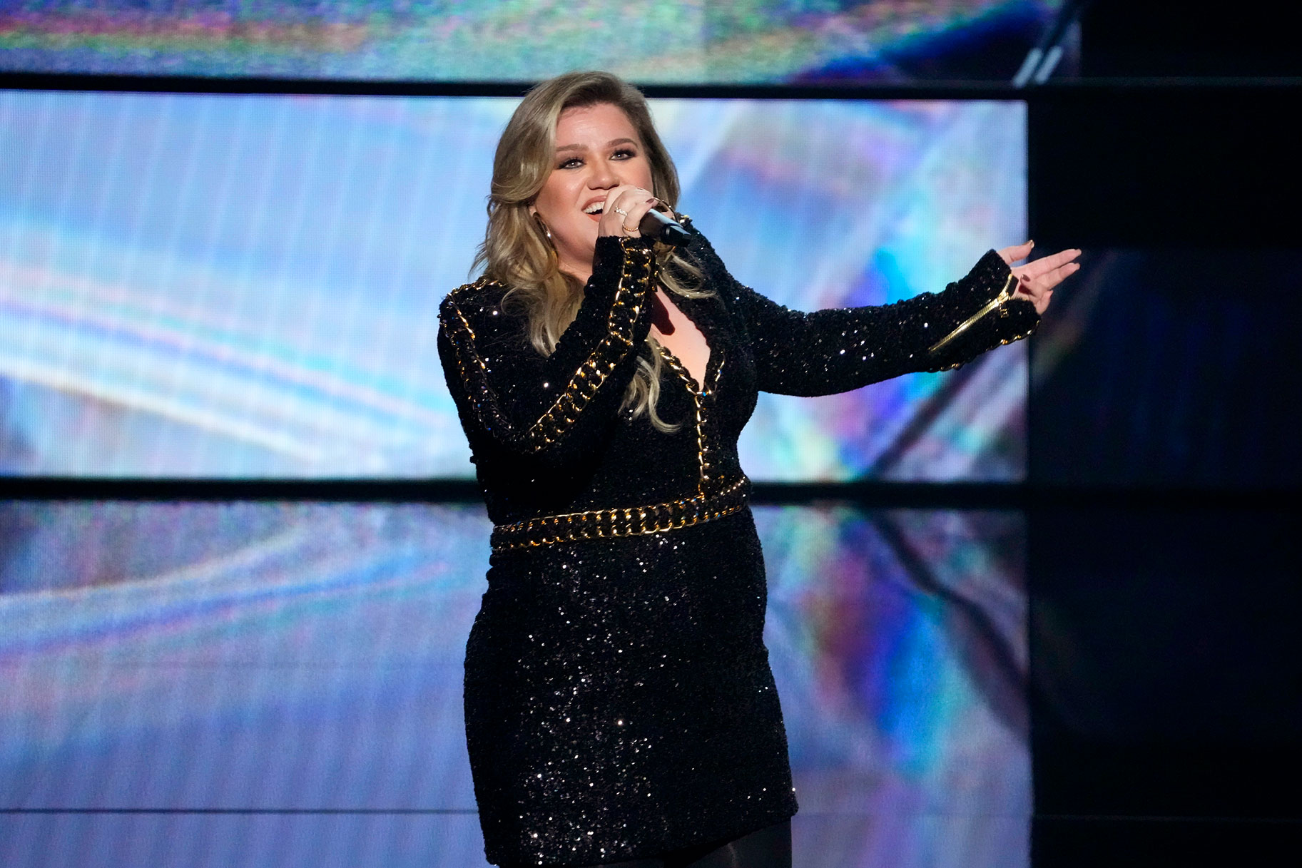 Kelly Clarkson performing onstage in a sparkly black dress