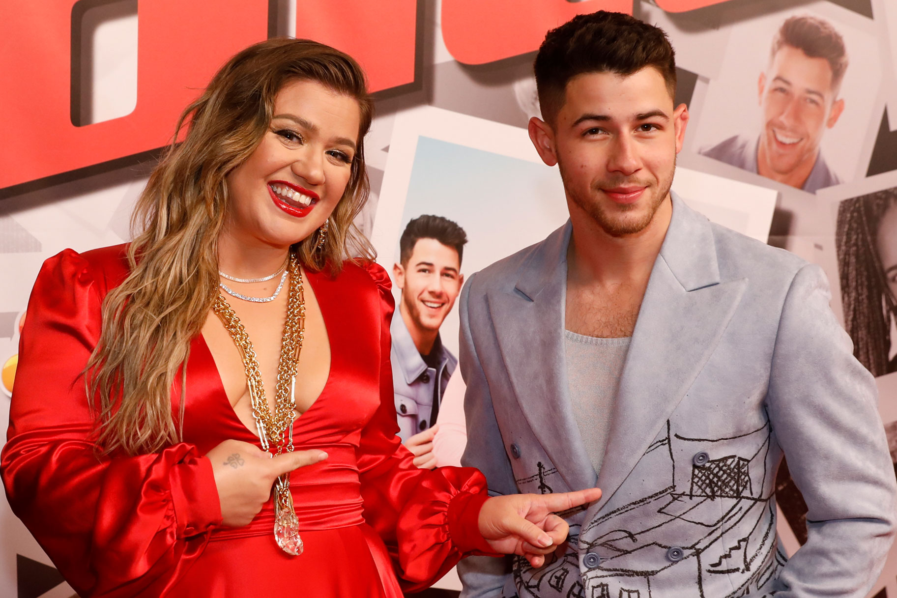 Kelly Clarkson posing and pointing at Nick Jonas on a red carpet