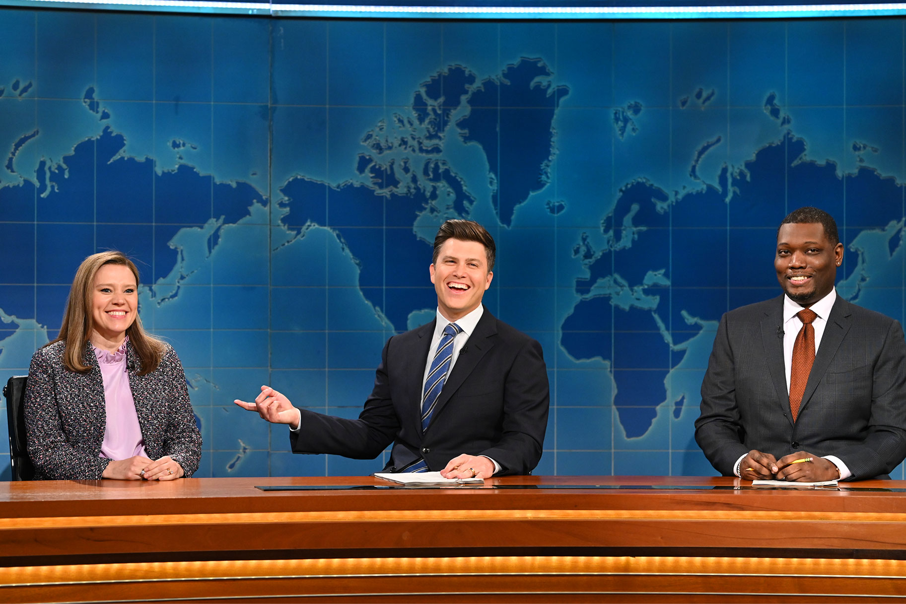 Kate McKinnon, Colin Jost, and Michael Che sitting at the weekend update desk