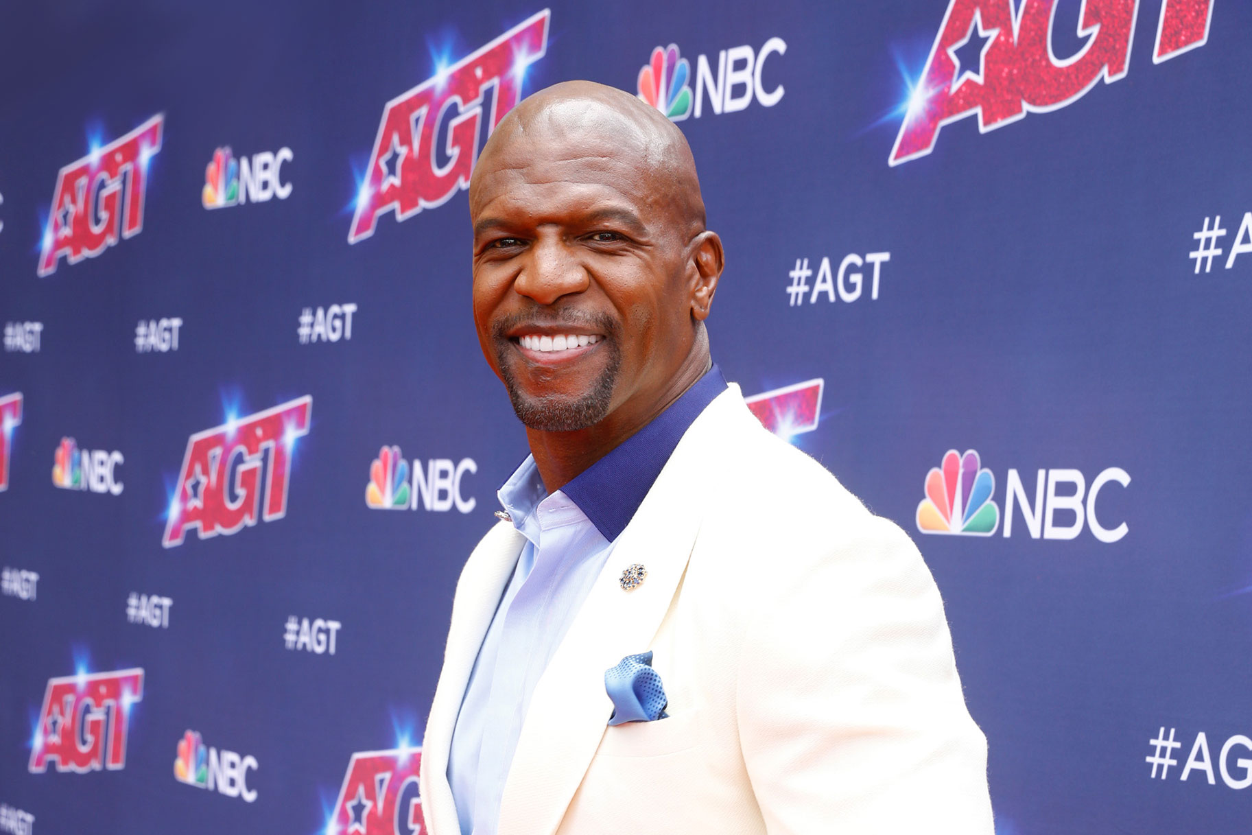 Terry Crews walking the America's Got Talent red carpet in a white suit