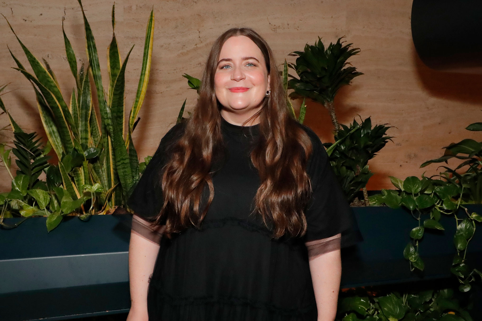 Aidy Bryant wearing a black dress and smiling at the camera