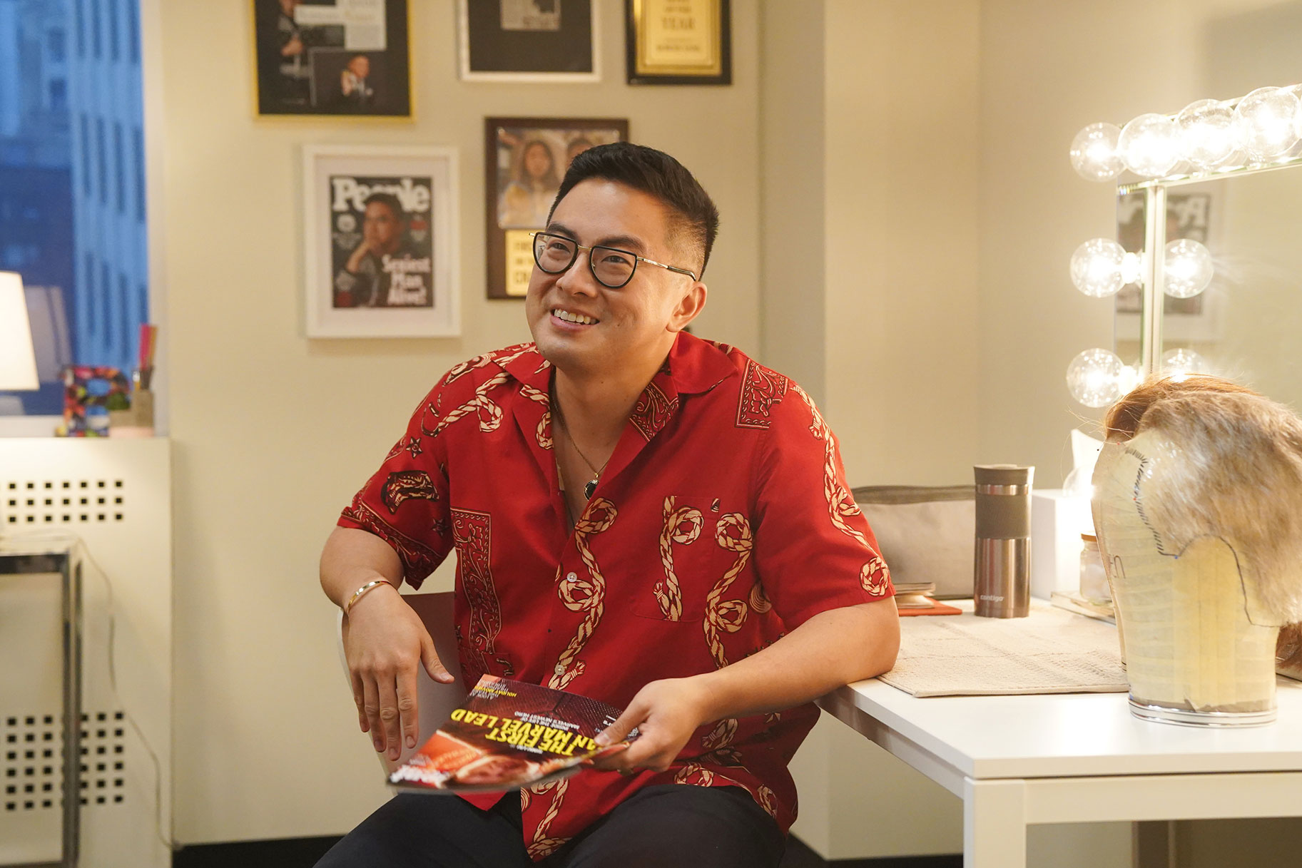 Bowen Yang seated in his dressing room, smiling