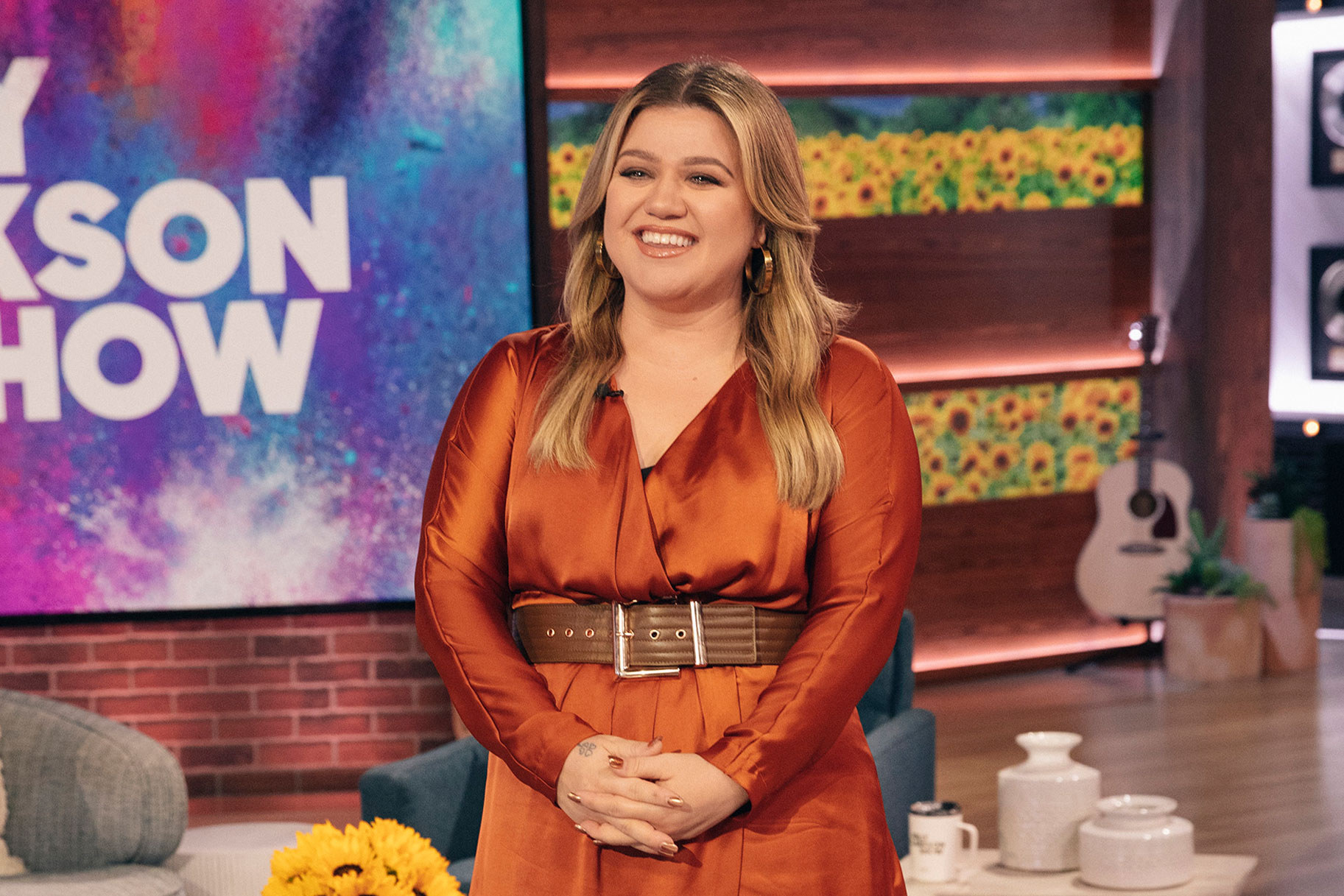 Kelly Clarkson standing on set of her talk show smiling