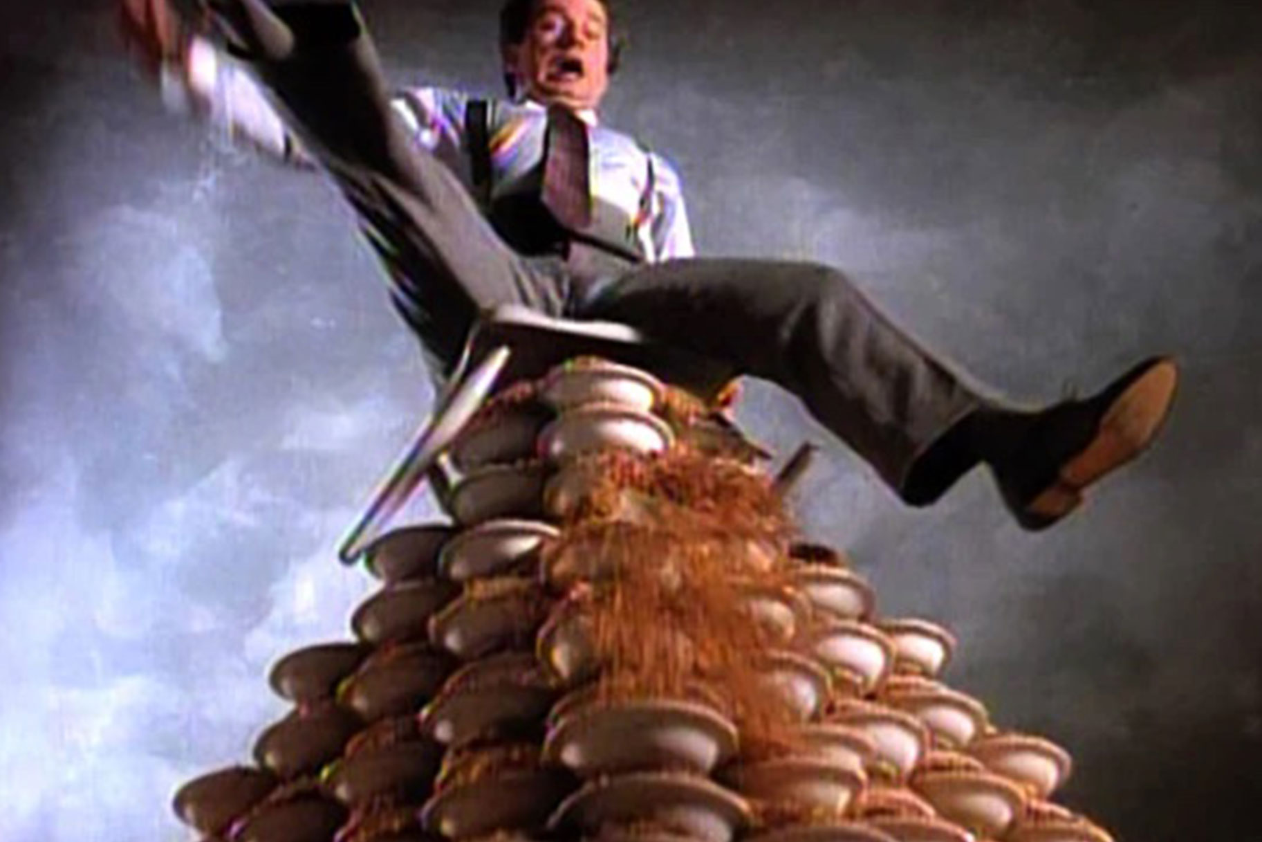 Phil Hatman sitting on a mountain of cereal bowls about to topple over