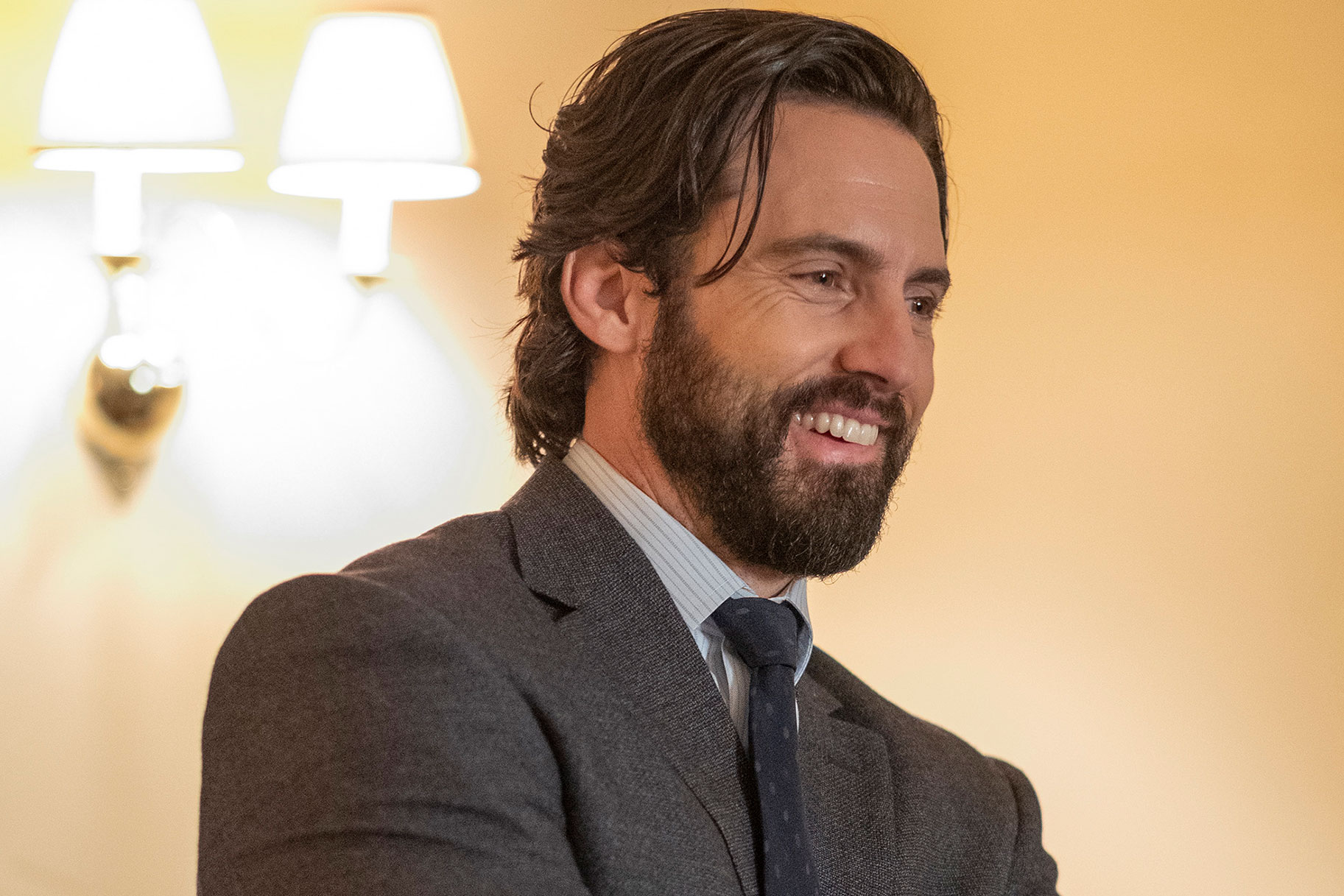 Milo Ventimiglia as Jack Pearson, smiling while wearing a grey suit