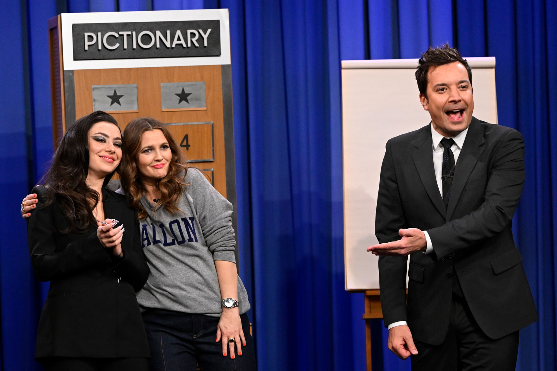 Charli XCX and Drew Barrymore embrace as Jimmy Fallon address the tonight show crowd