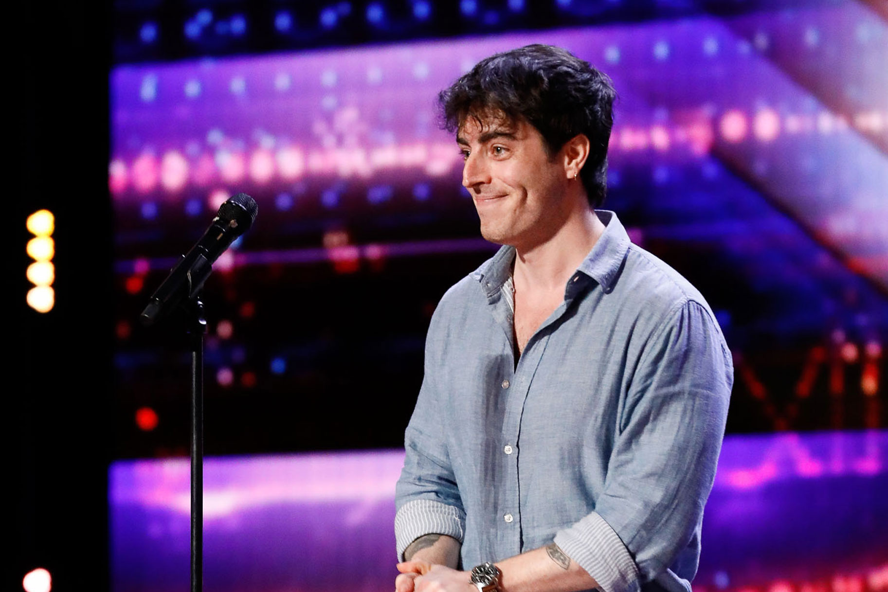 Sam Cieri standing on the AGT stage with a smile on his face