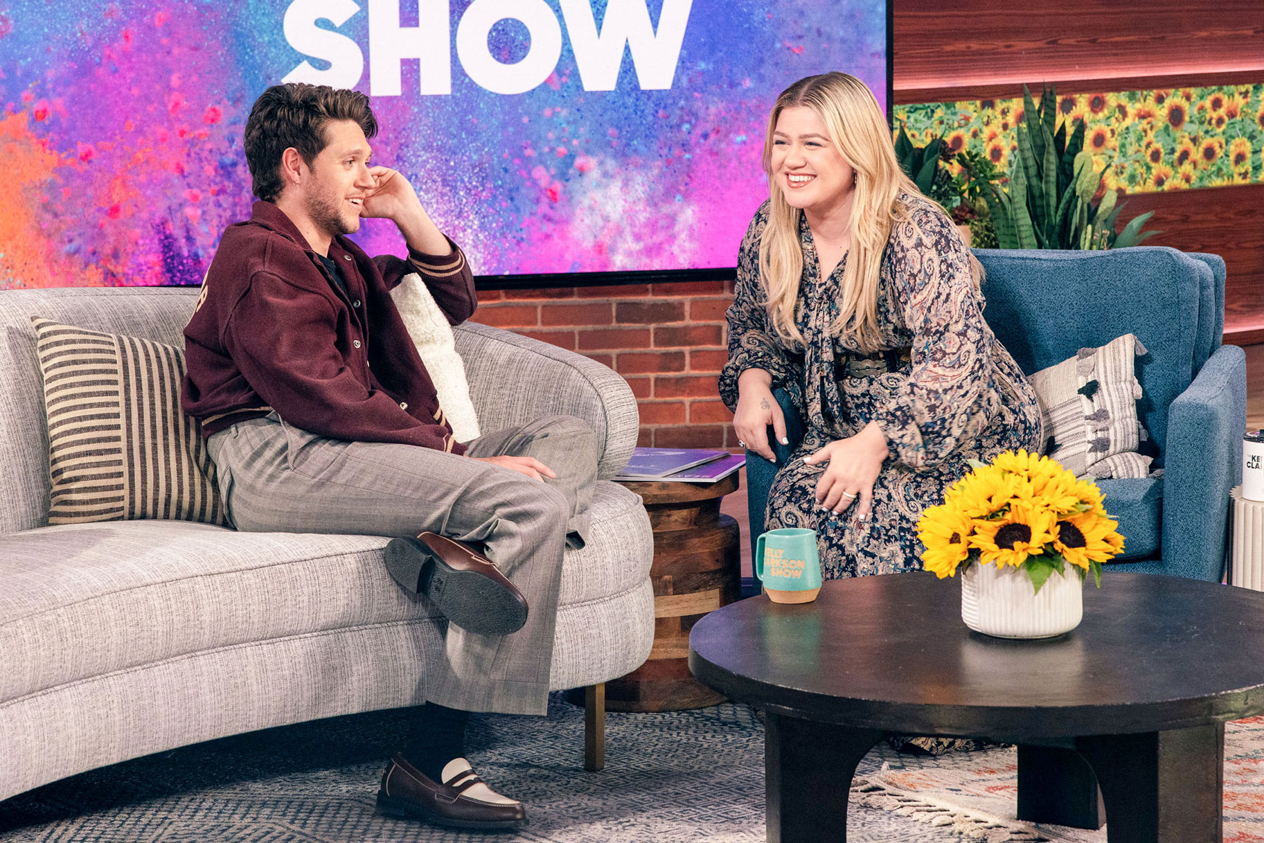 Niall Horan and Kelly Clarkson sitting on the couch of her talk show together