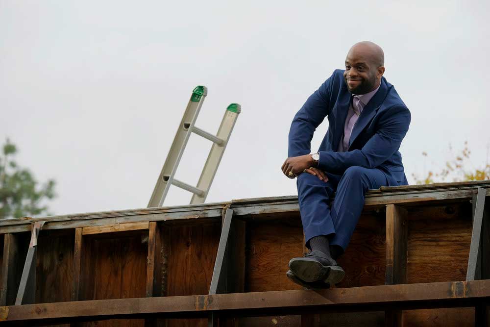 Isaiah appears on a roof in a scene from Killing It.