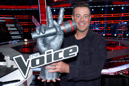 Carson Daly holding a sculpture of The Voice's logo