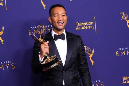 John Legend holding an Emmy Award in the Emmy's press room.