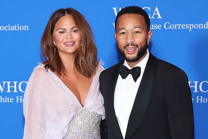 Chrissy Teigen and John Legend smiling and posing together at an event.