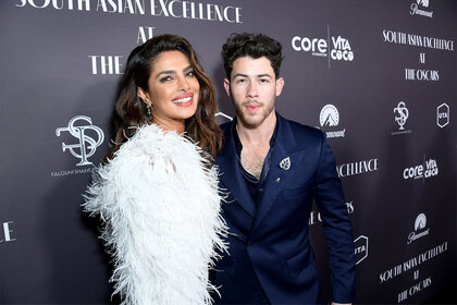 Nick Jonas and Priyanka Chopra Jonas smile during a red carpet ceremony