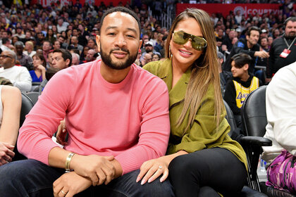 John Legend and Chrissy Teigen front row at a basketball game