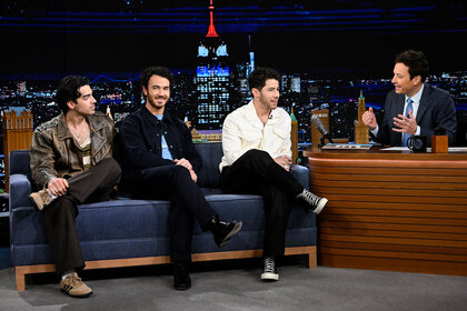 Jonas Brothers seated on the couch of the Tonight Show with Jimmy Fallon