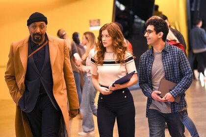 Alec Mercer, Phoebe, and Rizwan walking together throughout a group of people.