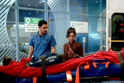 Bashir Hamed and Neeta Devi stand over a stretcher in the hospital.