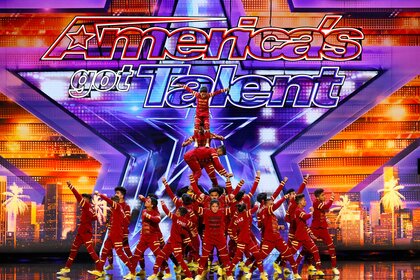 The group V. Unbeatable, wearing all red costumes, performing a dance number while balancing team members at the top.