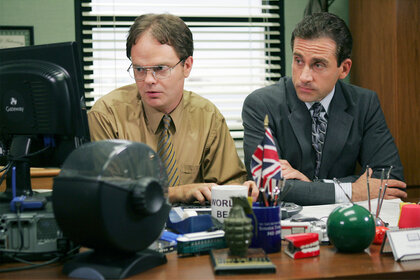 Rainn Wilson as Dwight Schrute and Steve Carell as Michael Scott sit at a computer together