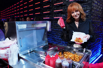 Reba McEntire eats tater tots during a segment on The Voice