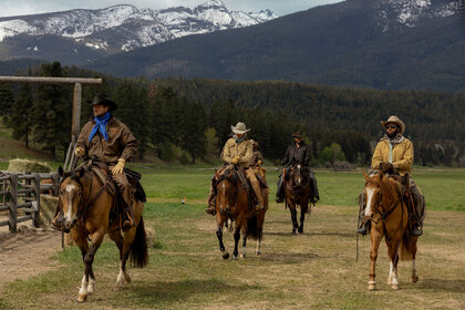 Four men ride horses on a ranch