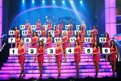 The Deal or No Deal briefcase models wearing magenta dresses and lined up in numerical order.