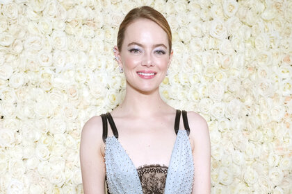 Emma Stone stands in front of a flower wall at he Academy Museum of Motion Pictures 2nd Annual Gala