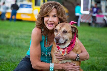 Linda Blair smiling and posing next to a dog.