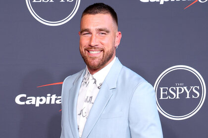 Travis Kelce wearing a light blue suit jacket smiles on the red carpet at the 2022 espy's