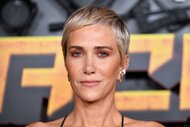 Kristen Wiig with blonde short hair smiling at the camera.
