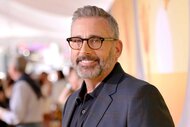 Steve Carell, wearing a black blazer and glasses, smiling and posing at an event.