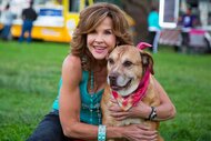 Linda Blair smiling and posing next to a dog.