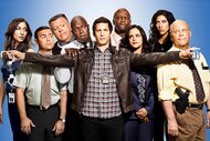 The cast of Brooklyn Nine-Nine Season 3 pose in front of a blue backdrop.