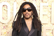 Lenny Kravitz wears dark sunglasses and a black suit to the 2024 golden globes