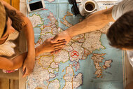 High angle view of a couple holding hands and choosing where to travel while examining a map.