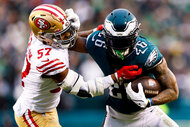 Miles Sanders #26 of the Philadelphia Eagles stiff arms Dre Greenlaw #57 of the San Francisco 49ers