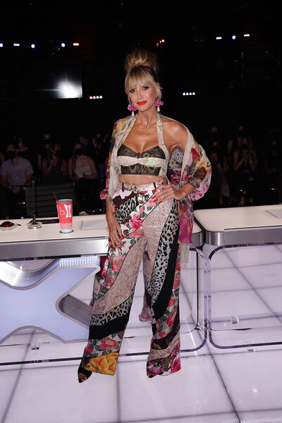 Heidi Klum wearing loose printed pants with a matching bralette and wrap