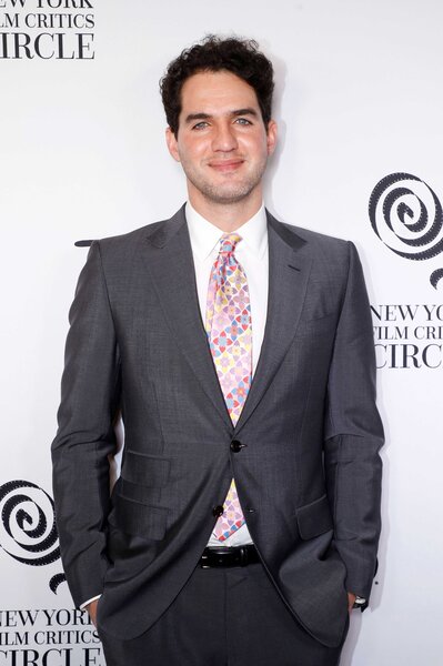 Benny Safdie attends an event wearing a gray suit and pink tie.
