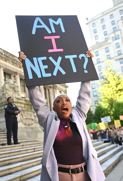 Kylie, with an upset look on her face, holds up a sign that says "Am I Next?".