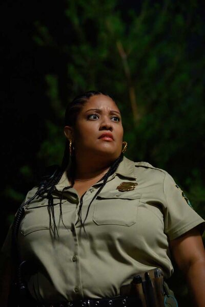 A close up of Taylor wearing a park ranger outfit in the dark.