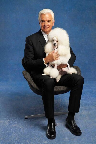 John O'Hurley sitting in a chair while a Miniature Poodle sits on his lap for The National Dog Show.