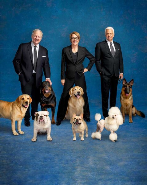 The National Dog Show judges posing together with various breeds of dogs.