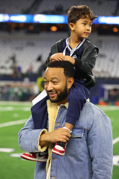 John Legend and Miles Stephens stand on the field at AT&T Stadium during the Dallas Cowboys game