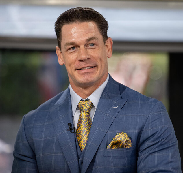 John Cena smiles in a blue suit with gold accessories.