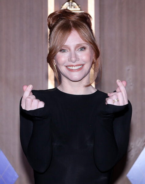 Bryce Dallas Howard holds up finger hearts in her black dress.