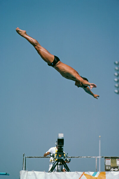 Greg Louganis dives into a pool at the springboard diving preliminary round in 1984