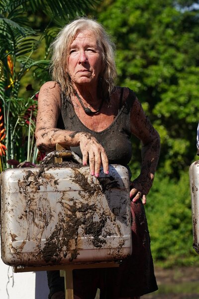 Kim Mattina leans on a muddy briefcase in Deal or No Deal Episode 101.