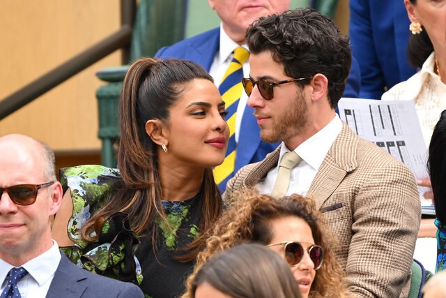 Priyanka Chopra and Nick Jonas whispering to each other while at a tennis match