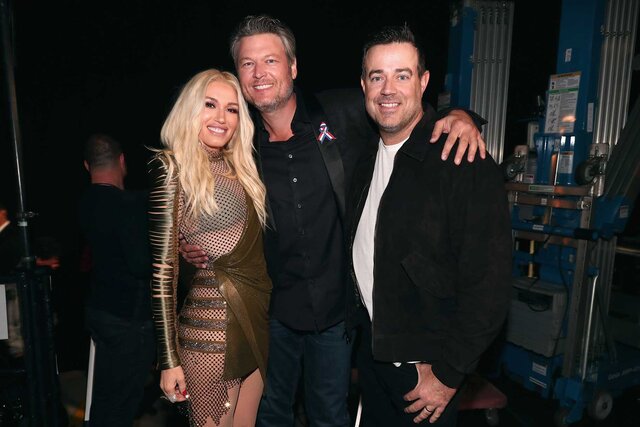 Gwen Stefani, Blake Shelton and Carson Daly hugging and posing for a photo.